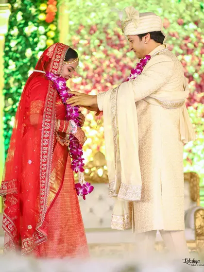 The groom helping the bride with her garland during the Varmala ceremony. It's a small, sweet gesture of care that makes for a wonderful candid shot.