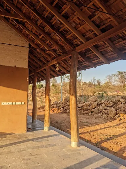 The veranda of the Unnathi Farm pavilion, with its reclaimed timber posts and stone flooring, looks out onto the rugged landscape.