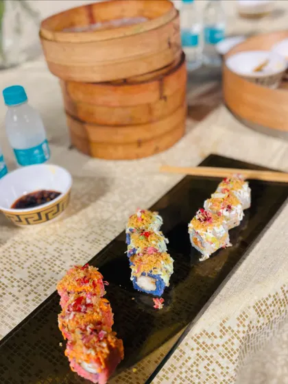 An artful presentation of colorful sushi rolls on a black slate platter.