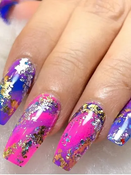 A galaxy in your hands. This vibrant design features a mix of pink and blue with scattered gold and silver foil flakes, creating a colorful and cosmic effect on long, square-shaped nails.