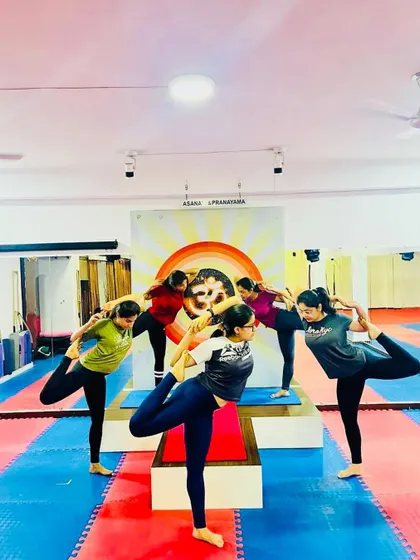 A group of students practicing Natarajasana (Lord of the Dance Pose) together. The synchronized effort creates a powerful sense of unity and shared focus.