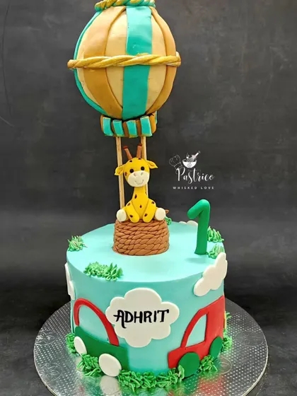 A whimsical hot air balloon cake for a first birthday adventure, featuring a cute fondant giraffe ready to take flight.