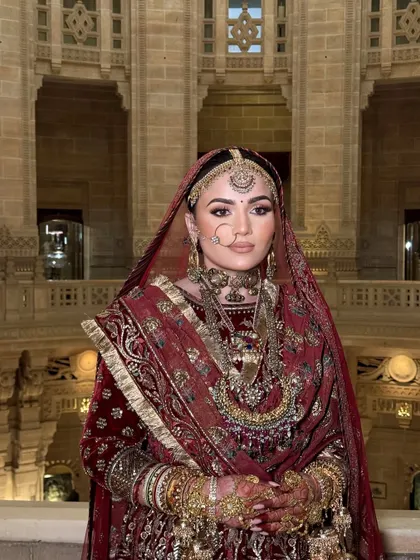 A frontal view of this majestic bridal look. The makeup was kept classic and clean to balance the heavy, traditional red velvet outfit and heritage jewelry.