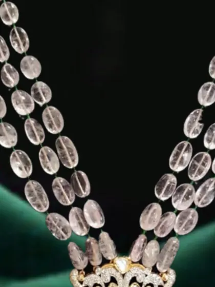 This royal necklace features strings of morganite beads leading to an intricate pendant. The design incorporates elephant motifs, polki, diamonds, and a touch of emerald for a truly unique heritage piece.
