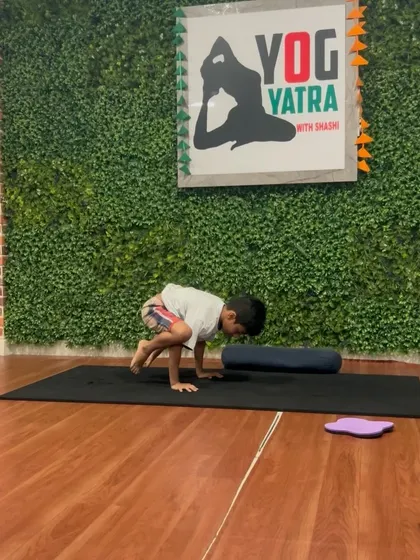 Using a bolster for support, this young yogi works on his arm balance skills.