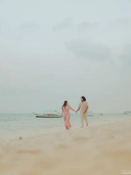 A wide shot of the couple walking hand-in-hand on the beach, emphasizing the vastness of the ocean and the intimacy of their connection within it.