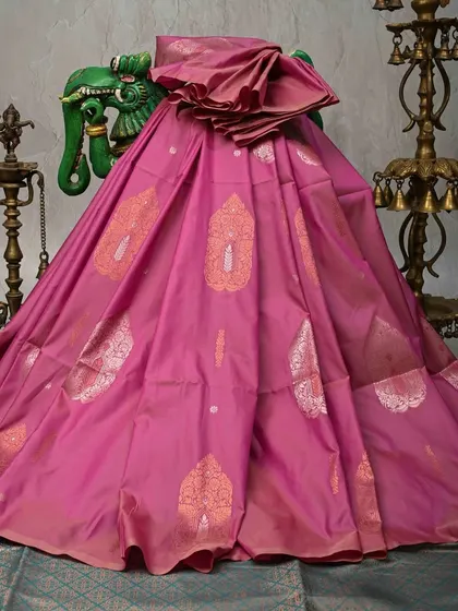 A lovely pink Banarasi silk saree with silver and gold paisley motifs. The soft color and intricate weaving make it a graceful choice for daytime weddings or festive pujas.