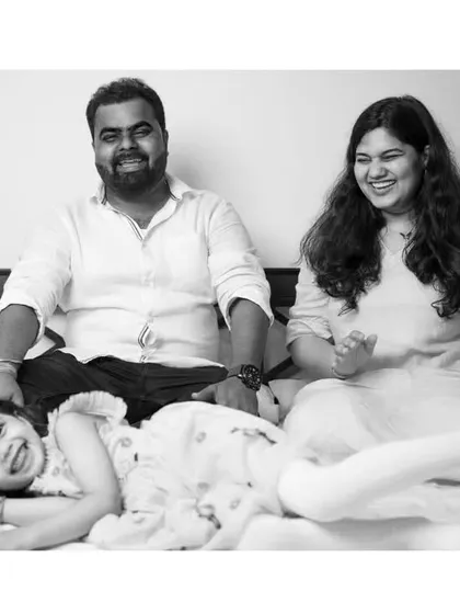A relaxed family moment captured in timeless black and white. The candid nature of the photo highlights their genuine smiles and connection.