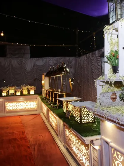 A wide view of one of our rustic-themed buffet setups. The white and gold counters are accented with hay and lanterns, creating a warm and inviting presentation for the food.