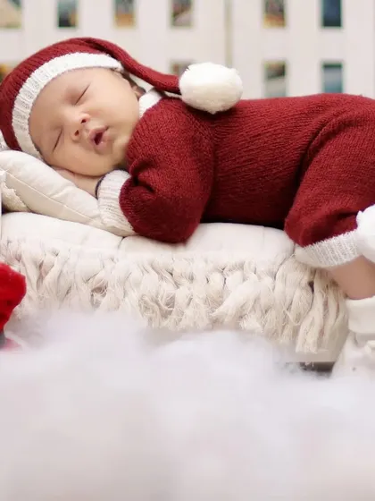 A full-body shot of the baby in a Santa outfit, nestled in soft white fluff. We prioritize your baby's comfort and warmth during all our sessions.