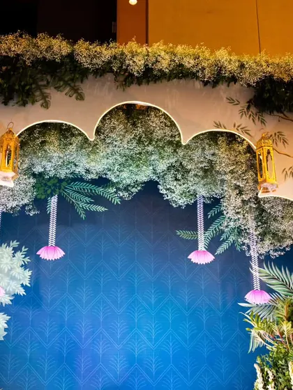 This custom photo backdrop features a printed nature scene with real floral overlays and hanging lanterns. It's a perfect example of how I mix different materials to create unique, multi-dimensional decor.
