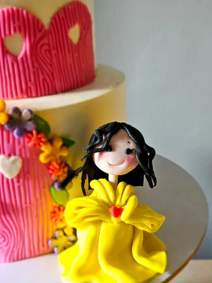 Pretty princesses in their castle. This two-tier whipped cream cake features a pink castle design and is adorned with three handmade princess figurines.