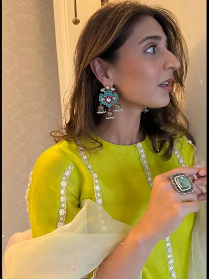 It's all in the accessories. This close-up highlights the colorful enamel and pearl jhumkas that add a pop of fun to the lime green outfit.