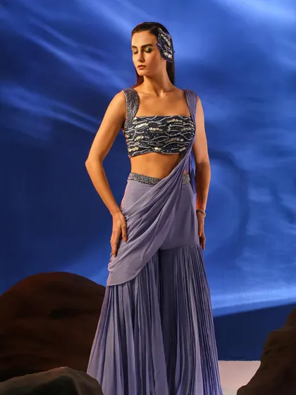 Another angle of the lavender sharara set, showing the full silhouette against the dramatic backdrop. The styling is consistent with the collection's ethereal theme.