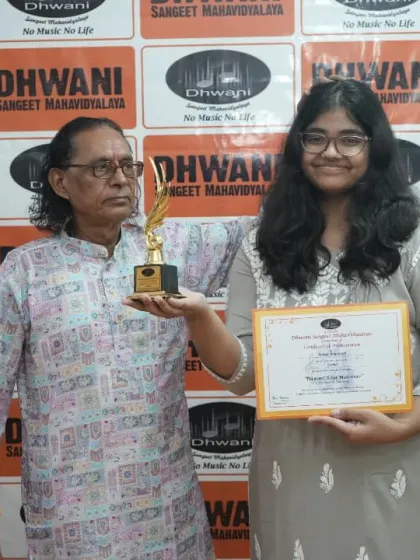 A senior guru presents an award to his student.