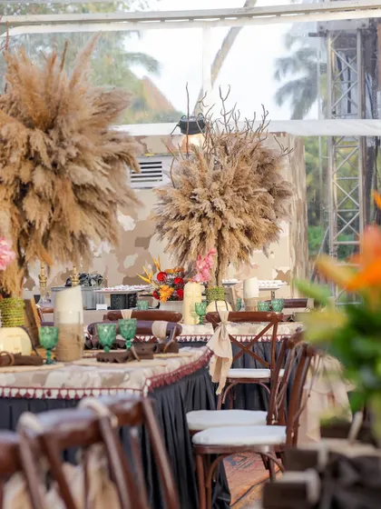 A dining table centerpiece featuring large plumes of pampas grass. This adds a soft, natural texture that contrasts beautifully with the wooden and floral elements.
