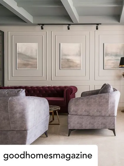 This living room from a featured project shows an English-inspired design with floor-to-ceiling wainscoting and a mix of vibrant and neutral upholstery. The coffered ceiling adds architectural depth to the space.