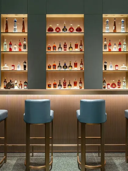 A detailed shot of the main bar at Armani Caffe. I focused on the symmetry of the shelving, the vibrant colors of the bottles, and the soft under-bar lighting to create a clean, compelling image that highlights the heart of the beverage service.