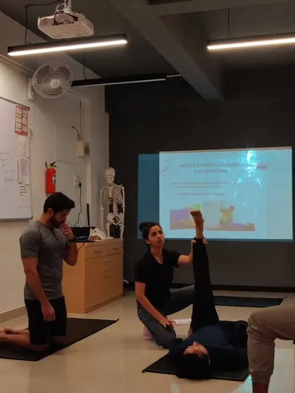 In a certified personal trainer course, demonstrating proper stretching techniques and discussing the anatomy behind the movement.
