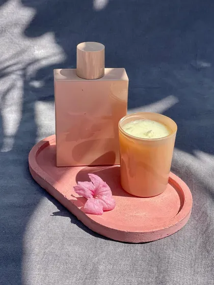 A simple, elegant pink concrete tray styled with a perfume bottle and a candle, showing how these pieces can elevate your dressing table.