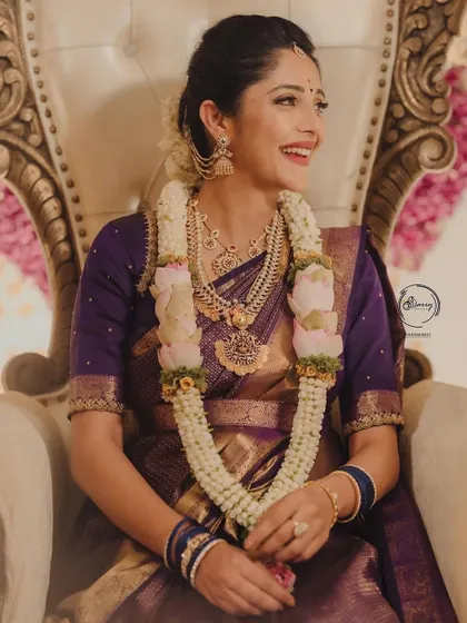 Milana's radiant smile during her baby shower, dressed in a traditional purple Kanjeevaram saree and custom blouse.