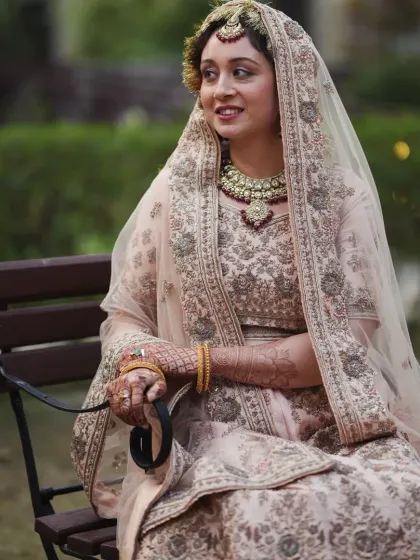 A portrait of a radiant bride in her pastel lehenga, seated and smiling, capturing the grace and happiness of her wedding day.