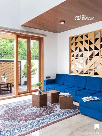 The living room of the Cube House opens onto a small patio. A geometric wooden screen acts as a decorative partition, adding visual interest while maintaining a connection to the outdoors.
