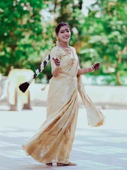 A joyful, candid shot of a woman in a beautiful saree, twirling with a happy expression. Her long, decorated braid adds to the traditional charm of the photograph.