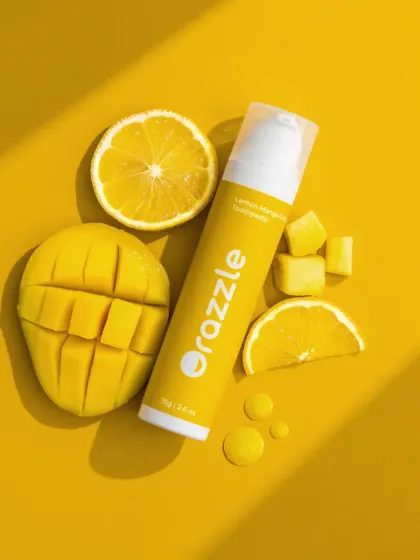 A top-down flatlay of Orazzle's lemon-mango toothpaste. The composition uses hard light to create sharp shadows, adding a graphic and modern feel to this ingredient-focused shot.