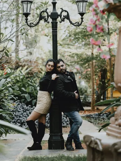 A romantic pose with a couple leaning against a lamppost in a lush park, perfect for an intimate pre-wedding photo.