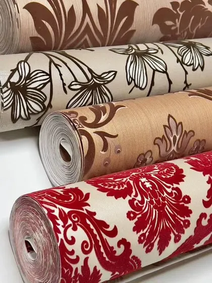 My velvet wallpaper collection offers a truly luxurious feel. This image displays several rolls with classic damask and floral patterns in rich colors like red and brown, highlighting their soft, touchable texture.