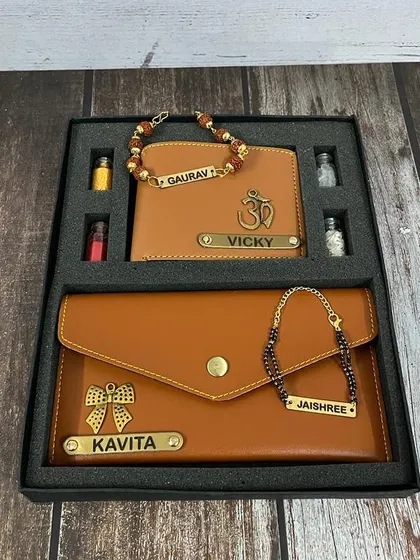 This Bhai-Bhabhi Rakhi set features a matching personalized wallet for him and a clutch for her in a classic tan color. The combo also includes a Rudraksh rakhi and a Mangalsutra bracelet.
