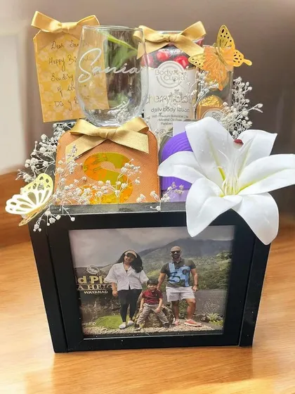 This personalized hamper features a custom photo frame at the front, making it extra special. The basket is filled with goodies and decorated with a beautiful white lily and delicate butterflies.