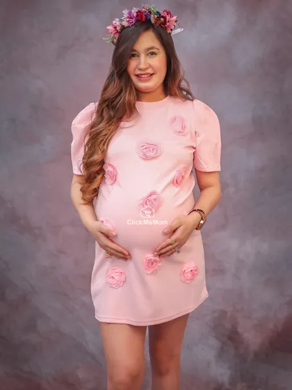 A sweet and feminine look with this lovely pink dress adorned with roses. The floral crown adds a touch of bohemian charm to this maternity portrait, perfect for celebrating a mom-to-be.