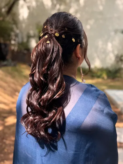 A detailed shot of the messy ponytail with gold accents. This hairstyle is perfect for adding a touch of modern artistry to any look.