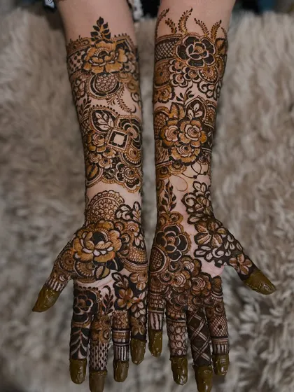 The henna paste is still on in this photo, showcasing the fresh application of a beautiful engagement floral design.