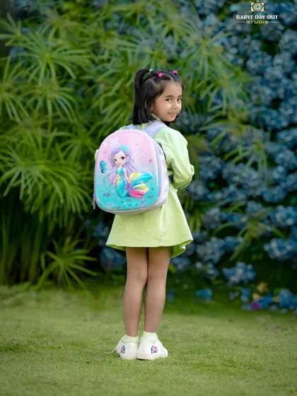 Ready for school! This little girl looks adorable with her mermaid backpack, posing in our garden before heading off on an adventure.