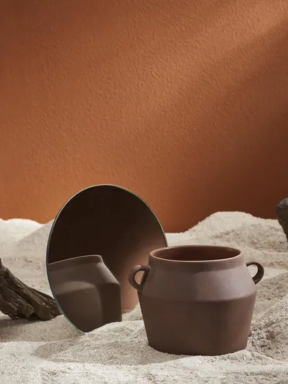 This art and decor photograph focuses on texture and reflection. The composition is a quiet study of form and color, designed to showcase the vase as a piece of sculptural art.