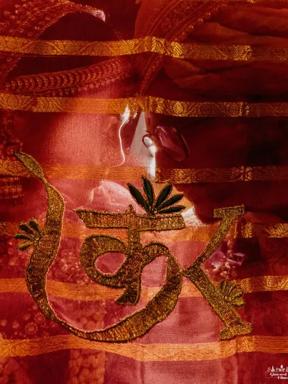 An artistic and creative shot of the bride, Kriti, seen through her red veil which is embroidered with the couple's initials.