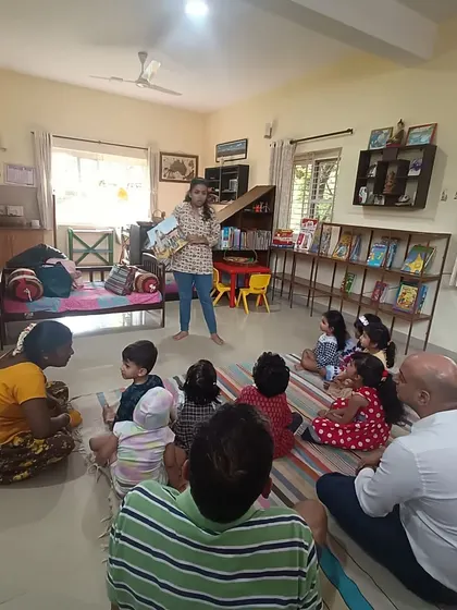 A wide view of a story session in progress, showing children and parents enjoying the tale together. Our library is a space for the whole family.