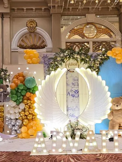 A stunning stage setup combining moon and stars, angel wings, and hot air balloon elements for a dreamy celebration.