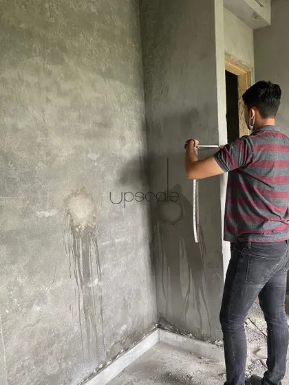 An architect taking precise measurements on a raw concrete wall. This is a fundamental step to ensure that custom furniture and fixtures will fit perfectly, leaving no room for error during installation.