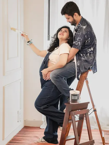 A playful and sweet moment captured. This couple shares a fun activity, painting a wall, symbolizing them building a new life together. It's a unique take on a couple's maternity shoot.