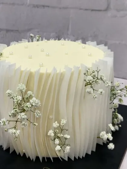 This elegant white cake with rice paper details and baby's breath is one of my most requested designs for sophisticated events.