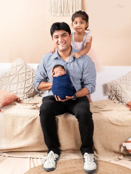 A proud father with his two children, the newest member sleeping peacefully in his arms.
