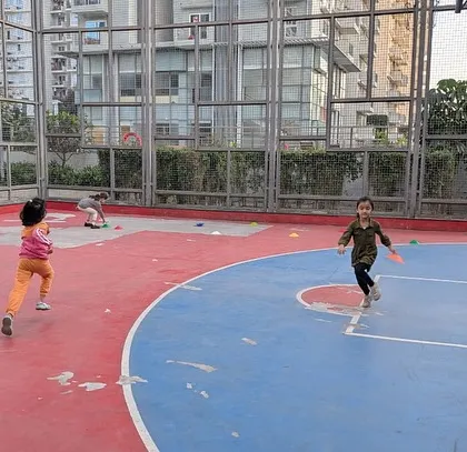 Kids playing a game of frisbee tag on a basketball court. We offer various sports classes and parties in apartment complexes.