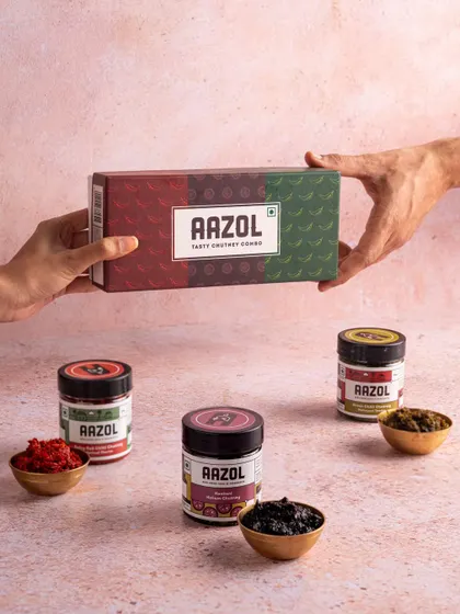 A shot of Aazol's chutney combo box being exchanged between two hands. This conveys the idea of gifting and sharing traditional flavors.
