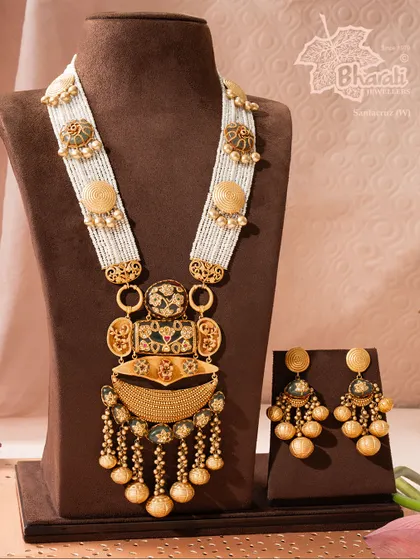 The Rajwadi Heritage Set captures the grandeur of royal India. This masterpiece, cast in pure 22ct gold, features a distinctive pendant and multi-strand pearl chains, embodying the grace and royalty of the queens it is inspired by.