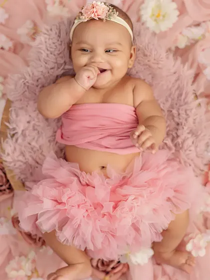 The pure, uninhibited joy of a four-month-old. Her giggles and chubby cheeks are just precious in this pink floral setup.