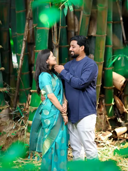 A lovely pre-wedding portrait taken in a bamboo forest, where the groom gently adjusts a strand of the bride's hair, showcasing a tender, caring moment.